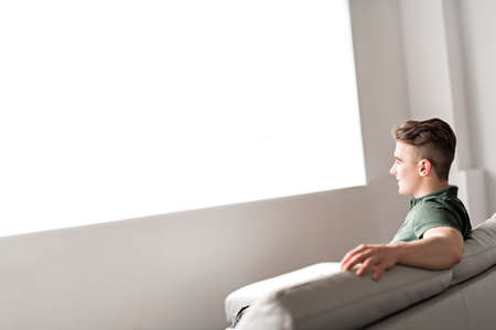 Handsome confident young man relaxing at home on the sofa