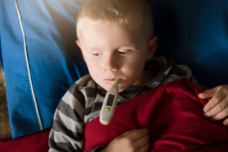 child sick in bed sleeping and testing fever