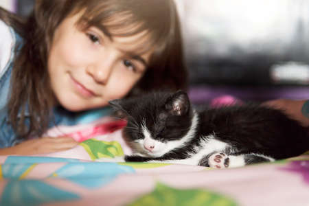 7 years old girl with kitten at home bed