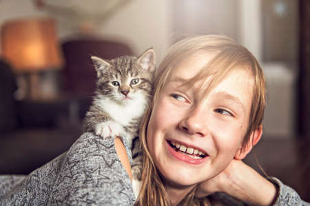 Preteen girl of 10 years old with her cat pet on the sofaの写真素材