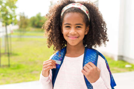 cheerful african american primary school girl with backpack