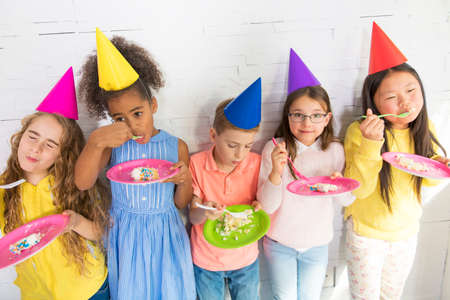 Group of adorable kids having fun at birthday party eat cake