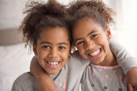Two little african american girls on bed at homeの写真素材