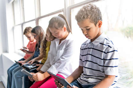 Group of curious children watching stuff on the tablet screenの写真素材