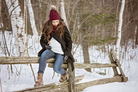 Young happy pregnant woman in snowy forest