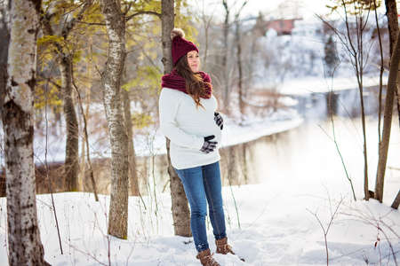 Young happy pregnant woman in snowy forest
