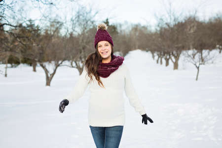 Young happy pregnant woman in snowy forest