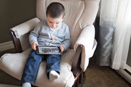Little boy using a digital tablet sit on the living roomの写真素材