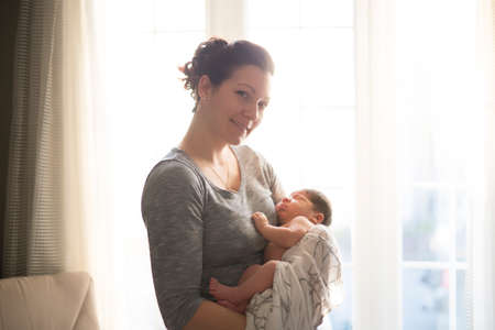 Happy mother holding adorable child baby on the living roomの写真素材