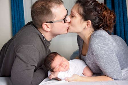 Happy family with newborn baby on the bed in the roomの写真素材