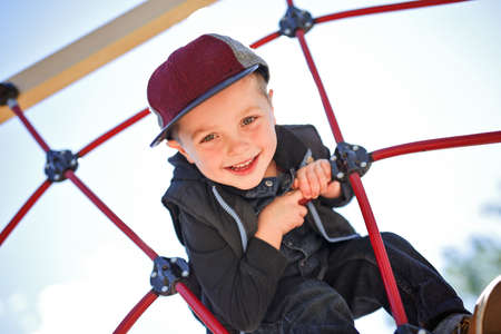 Happy little child boy climbed on playground