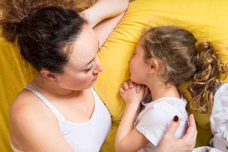 Mother and daughter at home in the bed.