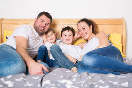 family, children and home concept - happy family with two kids under blanket at homeの写真素材