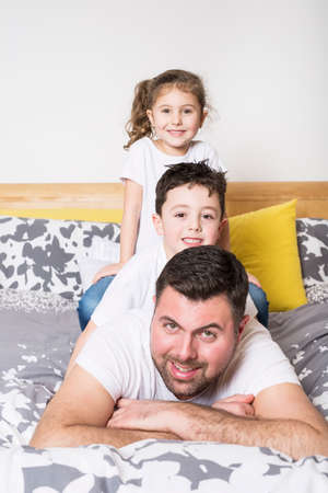 Man with two young children on bed smilingの写真素材