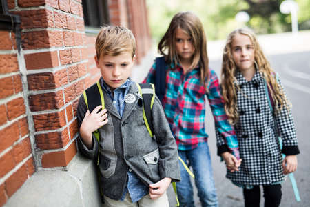 Pupils friends teasing a pupil alone primary schoolの写真素材