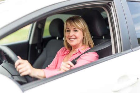 Happy and smiling senior woman in black car