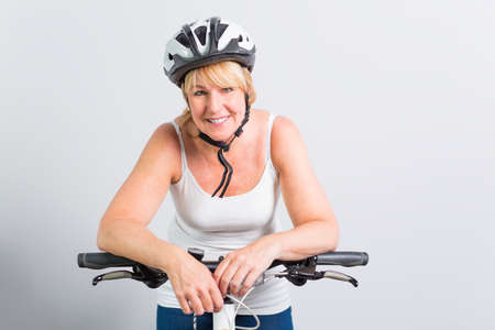 senior woman on the side of a bike in studio white backgroundの写真素材