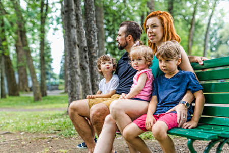 Happy family sitting on bench in parkの写真素材