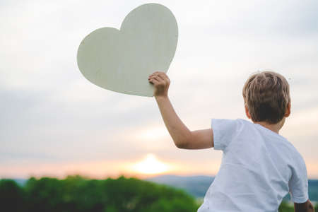 young boy in the meadow at the sunset holding heartの写真素材