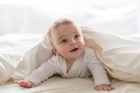 Cute happy 7 month baby girl in diaper lying and playing