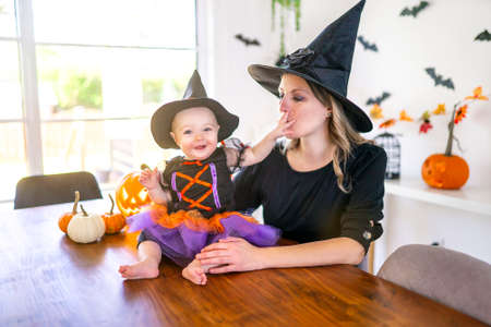 family mother and baby daughter on the kitchen table ready for the Halloween with pumpkinの写真素材