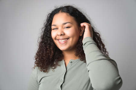 Studio portrait of beautiful brunette young dark-skinned woman on grey background