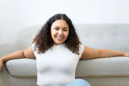 Attractive young African woman sitting on the couch at home