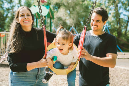 Happy family with two year sit on the swingの写真素材