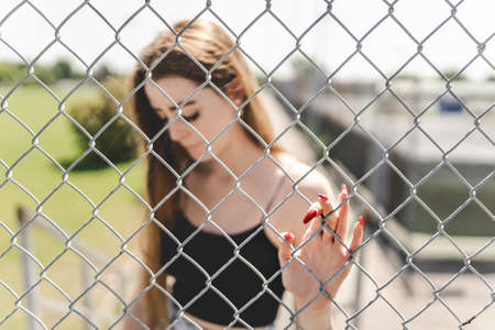Nice and sad teen girl standing portrait through fence