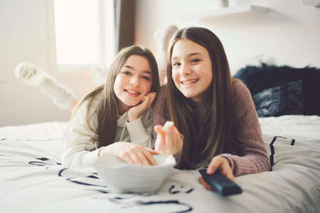 A pajama party with teens eat popcorn on the bedの写真素材