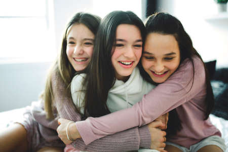 Three excited teenager girls having fun together, enjoying laze leisure time at homeの写真素材