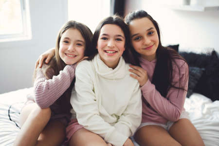 Three excited teenager girls having fun together, enjoying laze leisure time at homeの写真素材