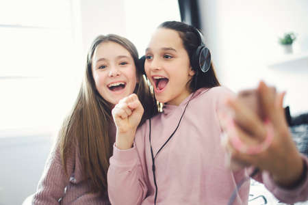 Two Teens spending time on bedroom at home to sing togerherの写真素材