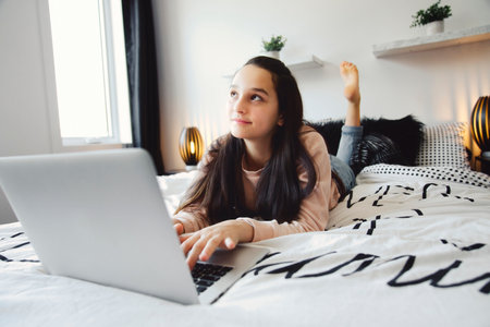Nice teenage girl using a computer in her bedroom.