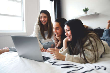 Teen friends using laptop on the bedroomの写真素材
