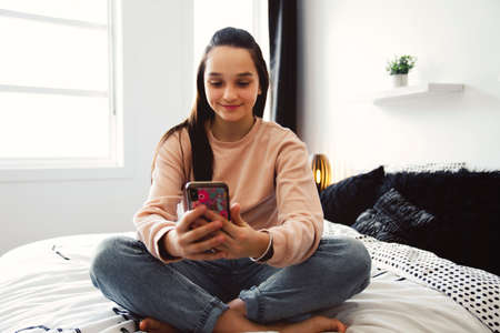 A teenage girl with smartphone on bed
