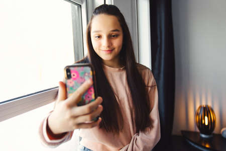 A teenage girl with smartphone on bedの写真素材