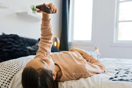 A teenage girl with smartphone on bed
