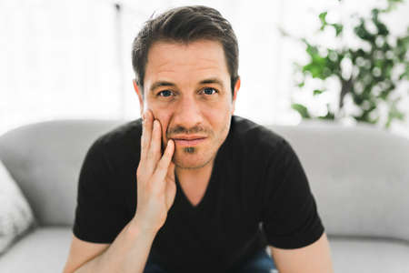 Depressed man thinking at home on couchの写真素材