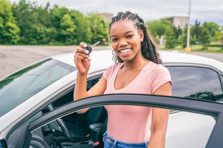 Young black teenage driver seated in her new car
