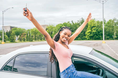 Young black teenage driver seated in her new car