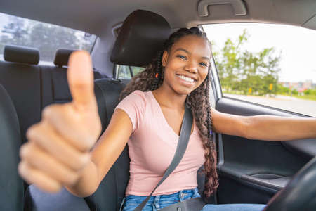 Young black teenage driver seated in her new car