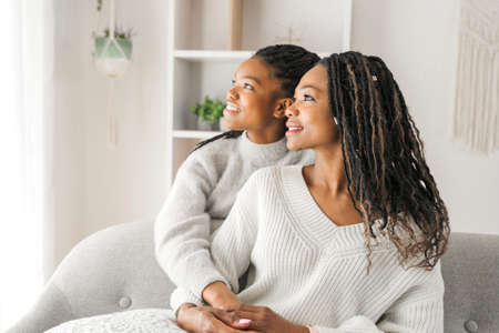 Mother and daughter sitting on sofa at home