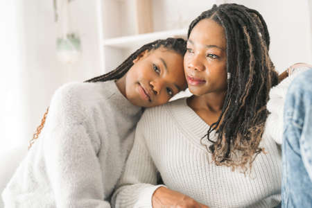 Mother and daughter sitting on sofa at home