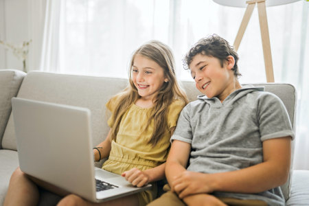 Youngs childrens using laptop on sofa in the living room at home