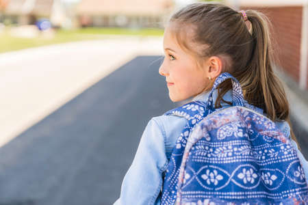 Young children girl on the school playground with backpack