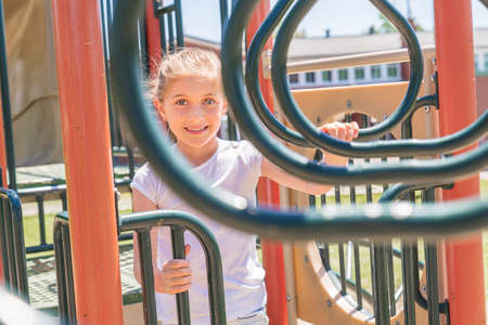 Active little girl having fun on playground on the summer timeの写真素材