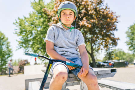 Portrait of young boy with scooter on parkの写真素材