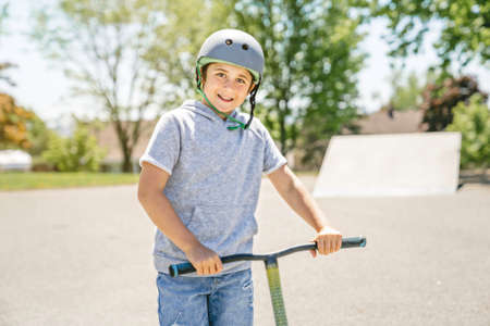 Portrait of young boy with scooter on parkの写真素材