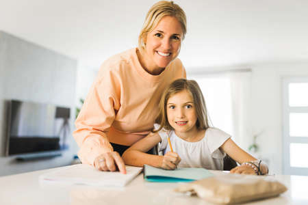 Mom helping kid with homework at homeの写真素材